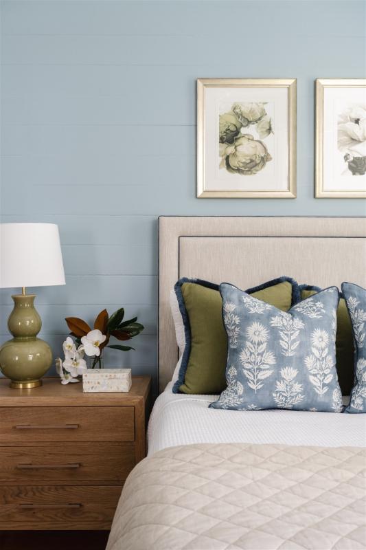 Close-up of bedside styling featuring a green ceramic lamp, magnolia blooms, and layered cushions in olive and blue, designed for Bella Vie Interiors’ Bardon retreat project.